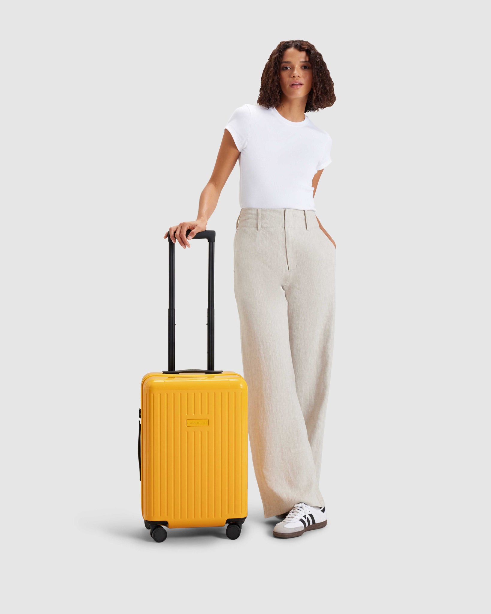 woman standing with yellow carry on suitcase